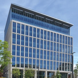 Photo of modern Manchester office building located in St Peters Square. Glass architecture with trees and people in the foreground. UK city environment with financial services buildings.